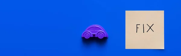 Top view of toy automobile near paper with fix inscription on blue background, banner — Stock Photo