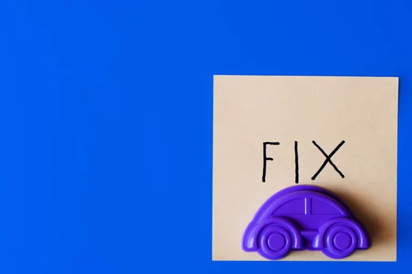 Vue du dessus de la voiture jouet violet et du papier avec lettrage fixe sur fond bleu — Photo de stock