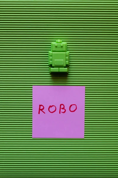 Top view of plastic toy near purple paper with robo inscription on green background — Stock Photo