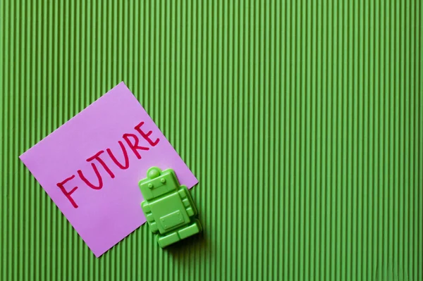 Top view of violet paper with future lettering near toy robot on green textured background — Stock Photo