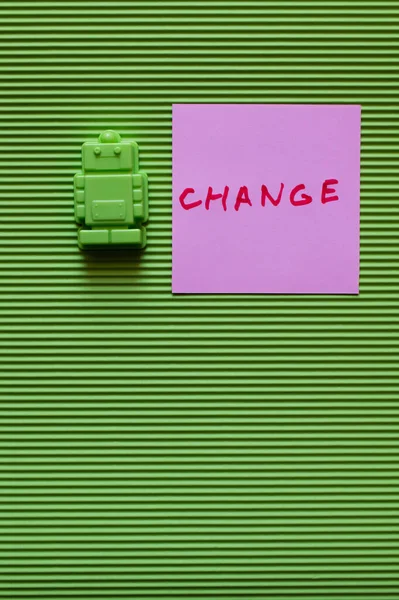 Top view of toy robot near purple paper with change inscription on green background — Stock Photo