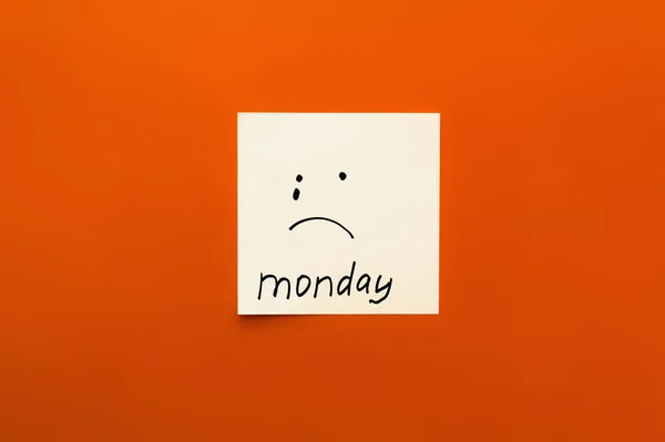 Vista superior da nota de papel com emoticon chorando e segunda-feira lettering no fundo laranja — Fotografia de Stock