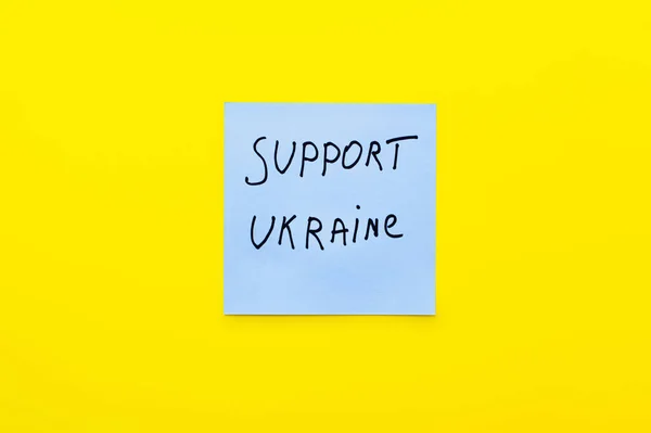 Vue du dessus du papier avec support lettrage ukraine sur fond jaune vif — Photo de stock