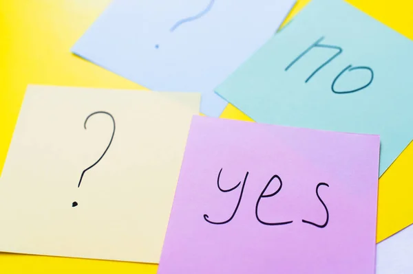 Multicolored papers with yes and no lettering near question marks on yellow background — Stock Photo