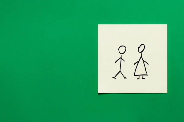 Top view of paper card with male and female icons on green background — Stock Photo