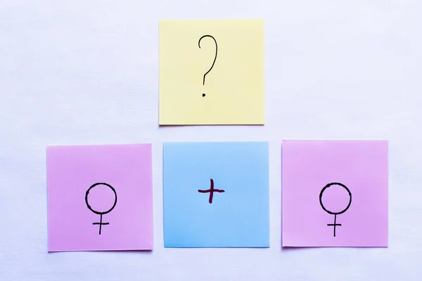 Top view of papers with plus sign and question mark near female symbols on white background — Stock Photo
