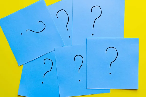 Top view of question marks written on blue cards on yellow background — Stock Photo