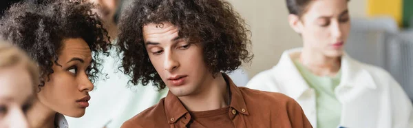 Young african american woman looking at curly classmate during lecture, banner — Stock Photo