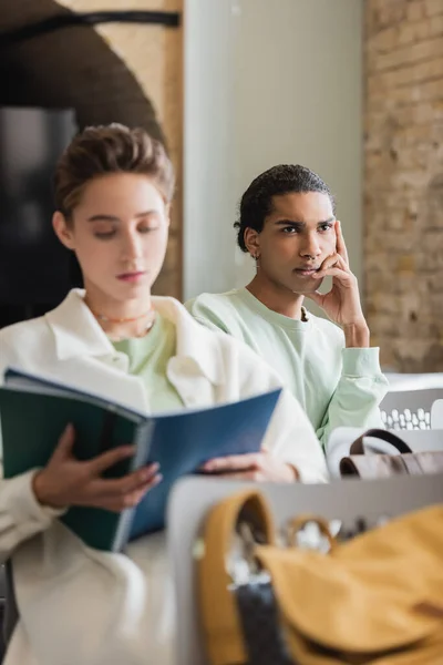 Reflexivo africano americano hombre escuchar conferencia cerca borrosa compañero de clase - foto de stock