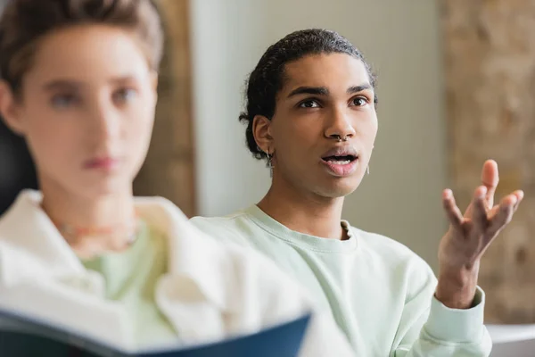 Découragé étudiant afro-américain pointant avec la main lors de la conférence près de femme floue — Photo de stock