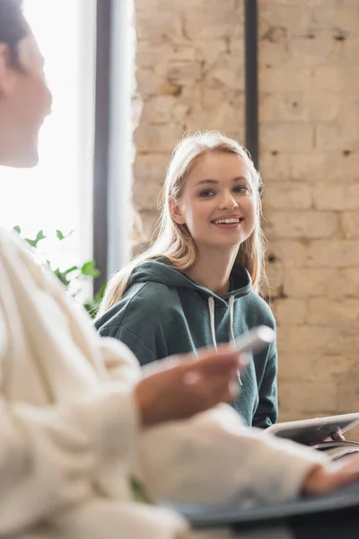 Jeune femme souriant à un ami flou lors d'une conférence à l'université — Photo de stock