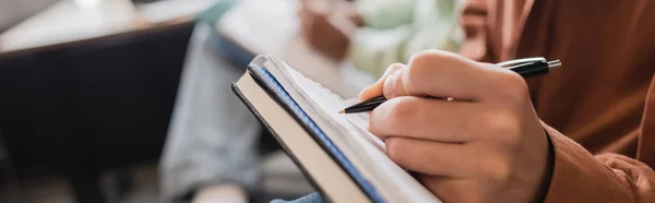 Partial view of student writing in copybook on blurred background, banner — Stock Photo