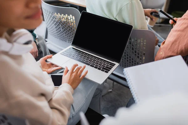 Cropped view of african american woman in classroom holding laptop with blank screen — Stock Photo