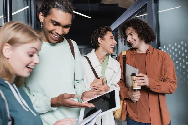 Lächelnder amerikanischer Student zeigt neben erstaunter Mitschülerin auf digitales Tablet — Stockfoto