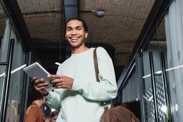 Allegro studente afroamericano con piercing in possesso di tablet digitale e guardando la fotocamera — Foto stock