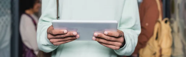 Visão parcial do estudante afro-americano segurando tablet digital em fundo embaçado, banner — Fotografia de Stock