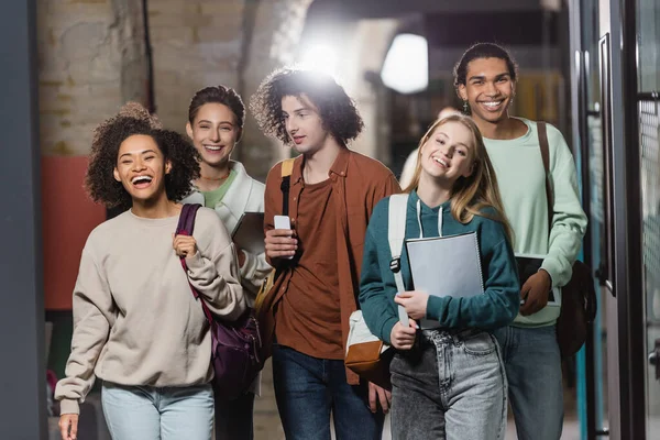 Excited african american woman laughing near multiethnic friends in university — Stock Photo