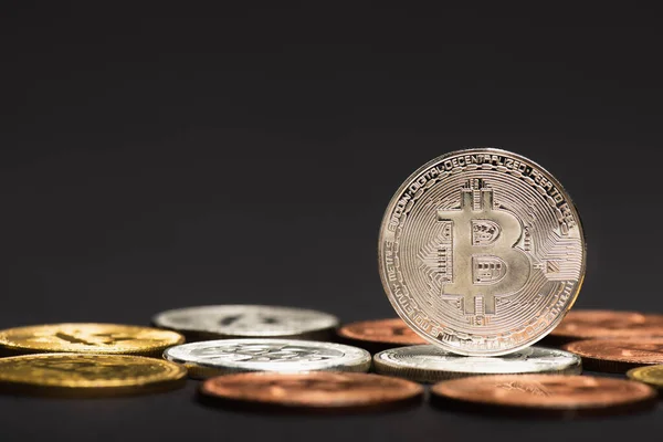 KYIV, UKRAINE - APRIL 26, 2022: Close up view of bitcoin on blurred coins on black background — Stock Photo