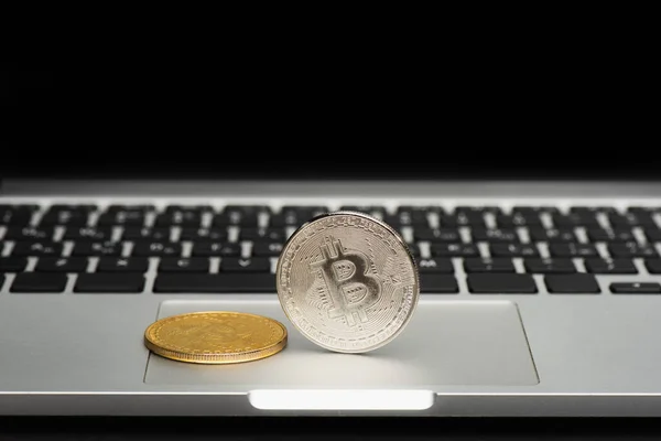 KYIV, UKRAINE - APRIL 26, 2022: Close up view of bitcoins on blurred laptop isolated on black — Stock Photo