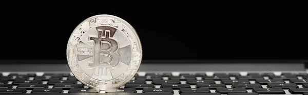 KYIV, UKRAINE - APRIL 26, 2022: Close up view of silver bitcoin on laptop with blank screen on black background, banner — Stock Photo