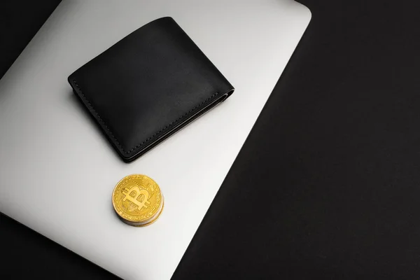 QUIIV, UCRÂNIA - 26 de abril de 2022: Vista superior da carteira e bitcoins no laptop isolado em preto — Fotografia de Stock