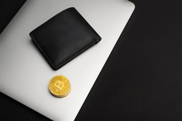 KYIV, UKRAINE - 26 AVRIL 2022 : Vue de dessus de portefeuille et bitcoins sur ordinateur portable isolé sur noir — Photo de stock