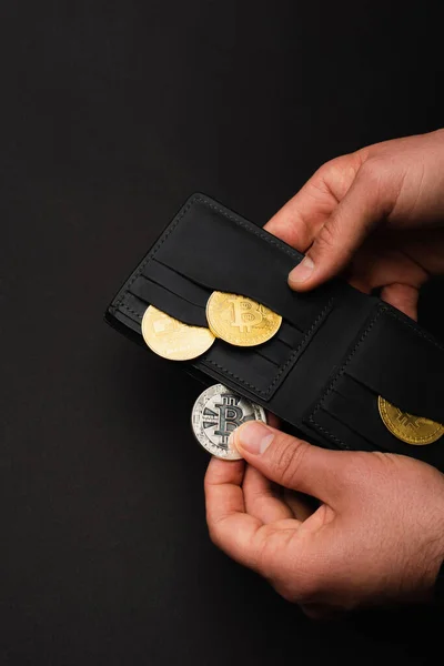 KYIV, UKRAINE - APRIL 26, 2022: Cropped view of man holding silver bitcoin and wallet isolated on black — Stock Photo