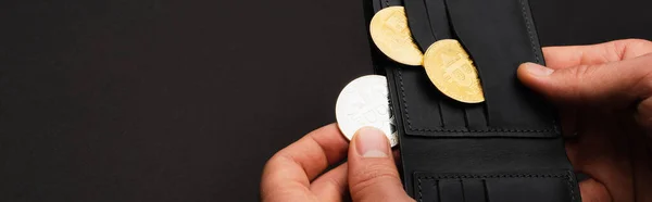 KYIV, UKRAINE - 26 AVRIL 2022 : Vue recadrée de l'homme tenant pièce de monnaie crypto-argent et portefeuille isolé sur noir, bannière — Photo de stock