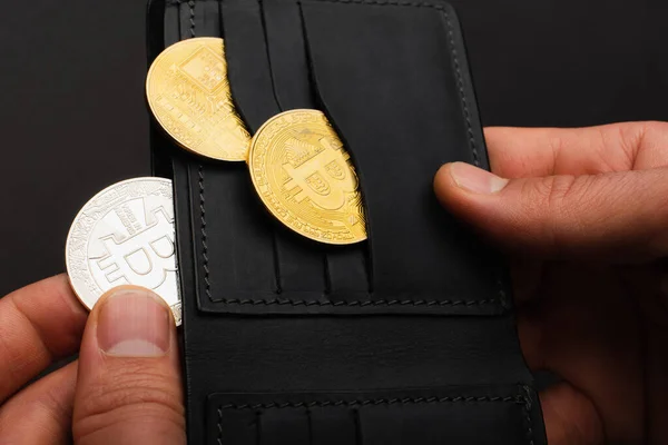 KYIV, UKRAINE - APRIL 26, 2022: Cropped view of man holding crypto coins and wallet isolated on black — Stock Photo