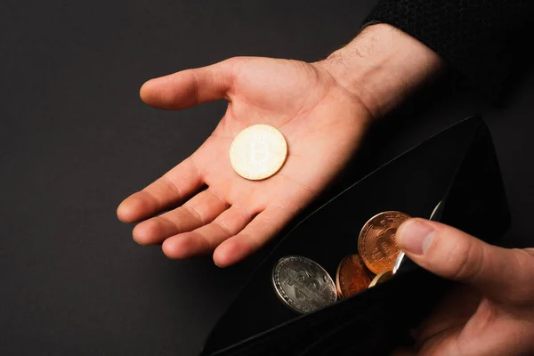 KYIV, UKRAINE - APRIL 26, 2022: Cropped view of man holding golden bitcoin and wallet isolated on black — Stock Photo