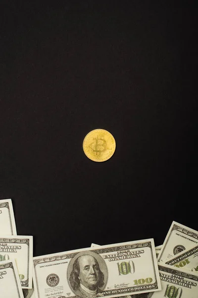 KYIV, UKRAINE - APRIL 26, 2022: Top view of golden bitcoin and cash isolated on black — Stock Photo