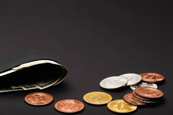QUIIV, UCRÂNIA - 26 de abril de 2022: Carteira com dinheiro perto de bitcoins diferentes em fundo preto — Fotografia de Stock