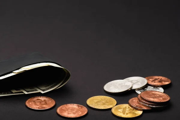 KYIV, UKRAINE - APRIL 26, 2022: Wallet with cash near different bitcoins on black background — Stock Photo