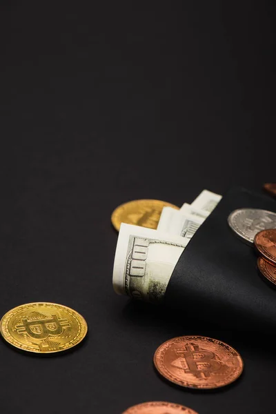QUIIV, UCRÂNIA - 26 de abril de 2022: Vista de perto de diferentes bitcoins e dólares em carteira sobre fundo preto — Fotografia de Stock