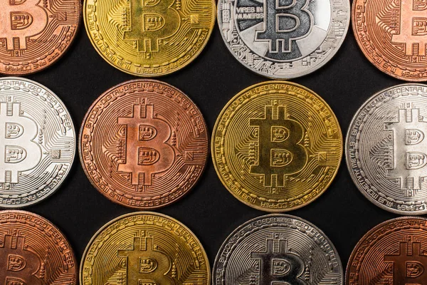 QUIIV, UCRÂNIA - 26 de abril de 2022: Vista superior de diferentes bitcoins isolados em preto — Fotografia de Stock