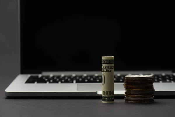 KYIV, UKRAINE - APRIL 26, 2022: Close up view of dollar near bitcoins and blurred laptop on black background — Stock Photo