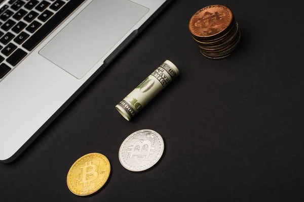 KYIV, UKRAINE - APRIL 26, 2022: Top view of dollar near bitcoins and laptop on black background — Stock Photo