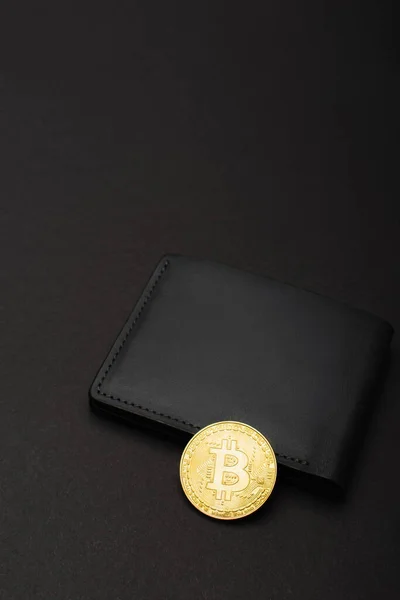 KYIV, UKRAINE - 26 avril 2022 : Vue en angle élevé de Bitcoin doré sur portefeuille sur fond noir — Photo de stock