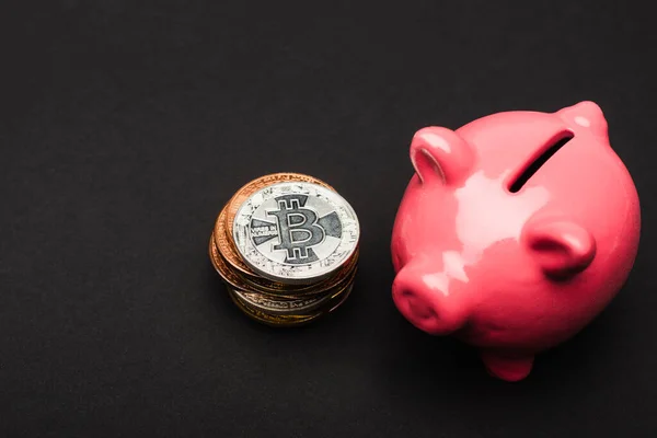 KYIV, UKRAINE - APRIL 26, 2022: Close up view of piggy bank and bitcoins on black background — Stock Photo