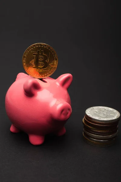 KYIV, UKRAINE - APRIL 26, 2022: Close up view of bitcoin on piggy bank on black background — Stock Photo