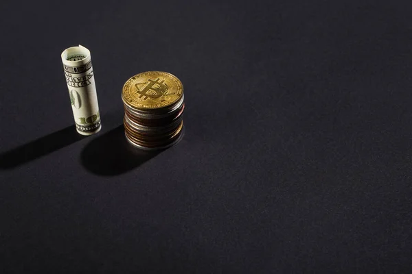 KYIV, UKRAINE - APRIL 26, 2022: High angle view of bitcoins near dollar on black background — Stock Photo