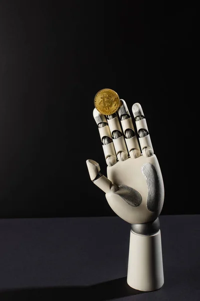 KYIV, UKRAINE - APRIL 26, 2022: Bitcoin and robotic hand on black background — Stock Photo