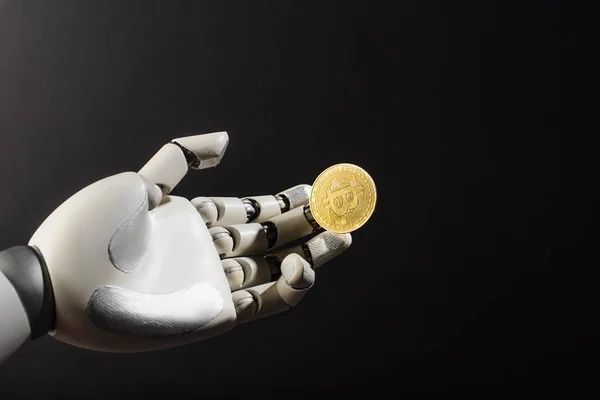 KYIV, UKRAINE - APRIL 26, 2022: Golden bitcoin on robotic hand isolated on black — Stock Photo