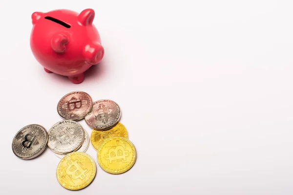 KYIV, UKRAINE - APRIL 26, 2022: High angle view of cryptocurrency and pink piggy bank on white background — Stock Photo