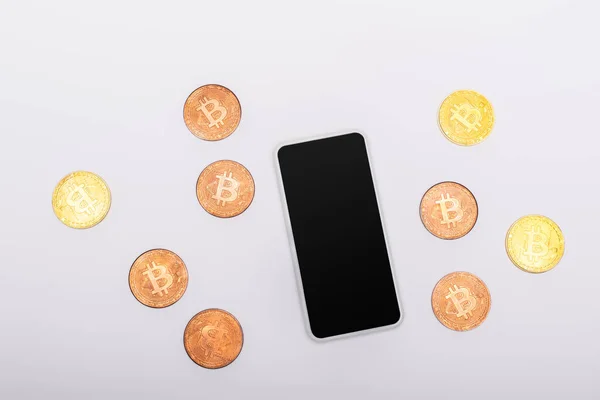 KYIV, UKRAINE - APRIL 26, 2022: Top view of cellphone with blank screen near crypto coins on white background — Stock Photo