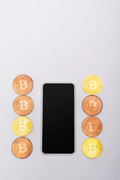 KYIV, UKRAINE - APRIL 26, 2022: Top view of cryptocurrency near mobile phone with blank screen on grey background — Stock Photo
