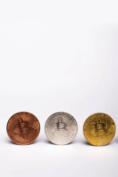 QUIIV, UCRÂNIA - 26 de abril de 2022: Vista aproximada de diferentes bitcoins sobre fundo branco com espaço de cópia — Fotografia de Stock