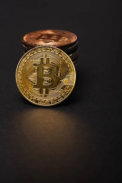 KYIV, UKRAINE - APRIL 26, 2022: Close up view of golden bitcoin near cryptocurrency on black background — Stock Photo