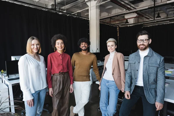 Heureux agents de publicité multiethnique regardant caméra dans le bureau — Photo de stock