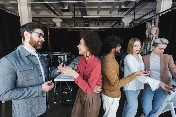 Lächelnde multikulturelle Werbemanager gestikulieren während der Diskussion im Amt — Stockfoto